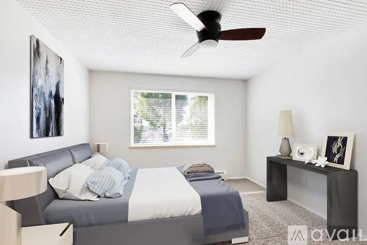 A bedroom with a bed, nightstand, and a fan.
