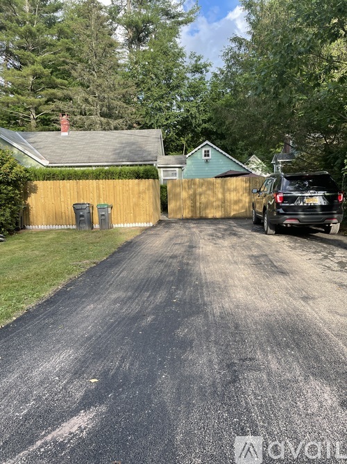 A black car is parked on a driveway.