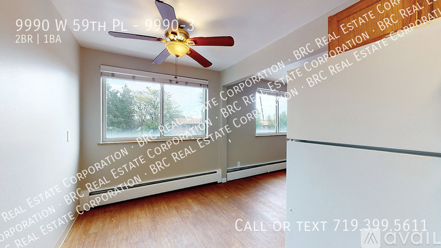 A room with a ceiling fan and a window showing trees outside.