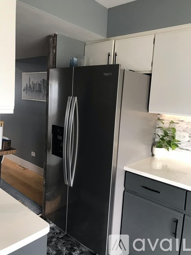 A black refrigerator in a kitchen with a white counter.