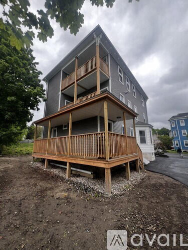 A wooden deck is in front of a grey building.