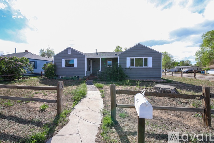 A grey house with a white mailbox in front of it.