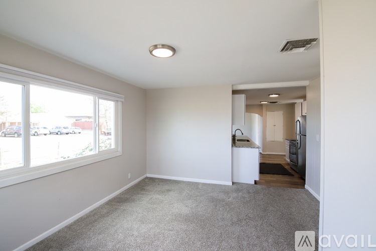 A spacious room with a carpeted floor and a window overlooking a parking lot.