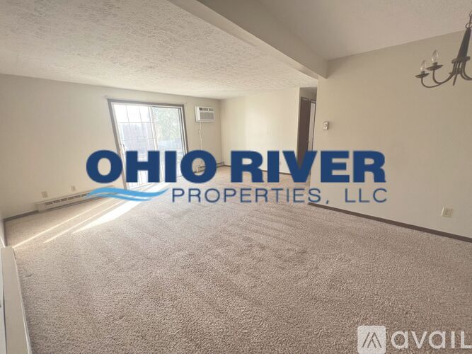 A room with carpet flooring and a window with a view of trees outside.