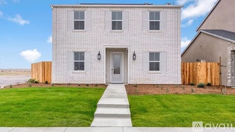 A two-story house with a grey brick exterior and a wooden fence.
