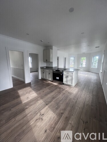 A spacious room with wooden floors and white walls.