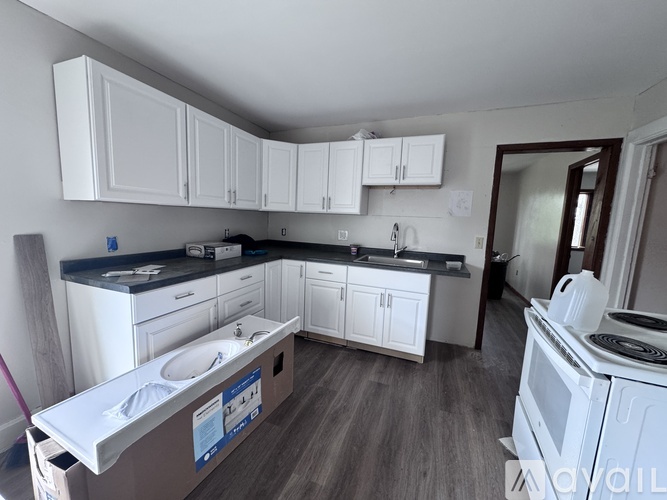 A kitchen with white cabinets and a wooden floor.
