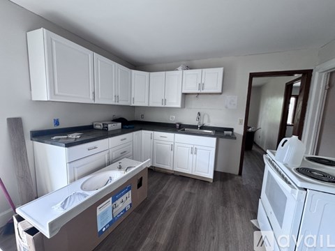 A kitchen with white cabinets and a wooden floor.