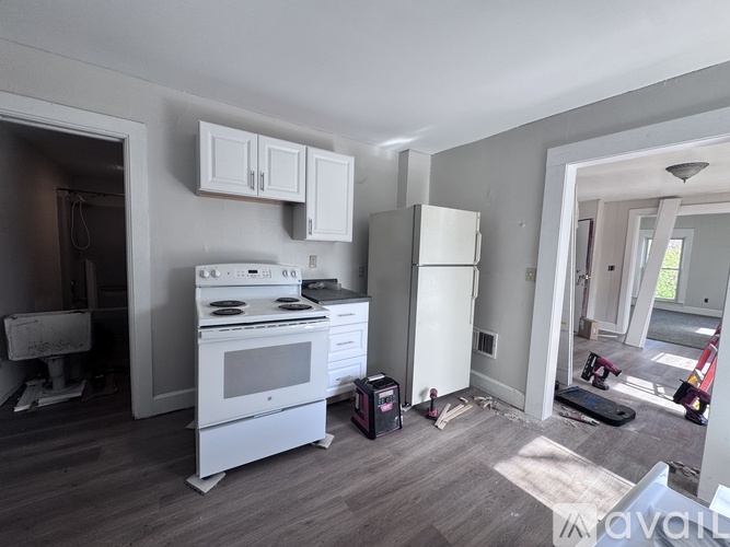 A kitchen with a white stove and cabinets is under renovation.
