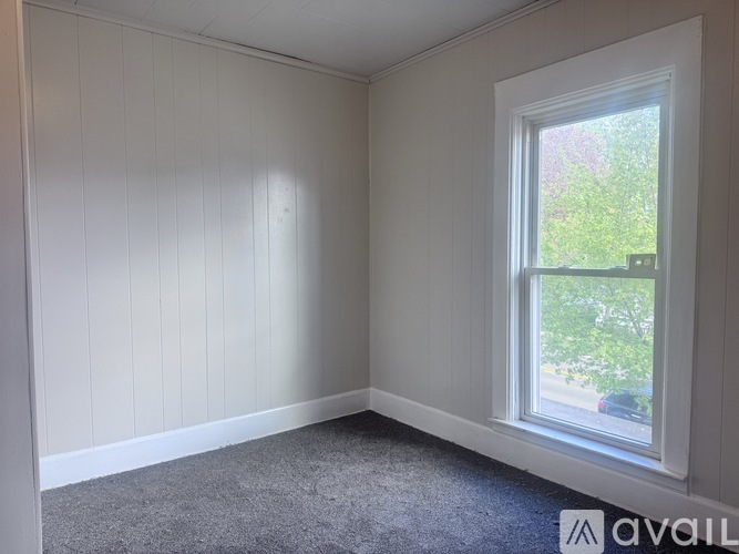 A room with a window and a carpeted floor.