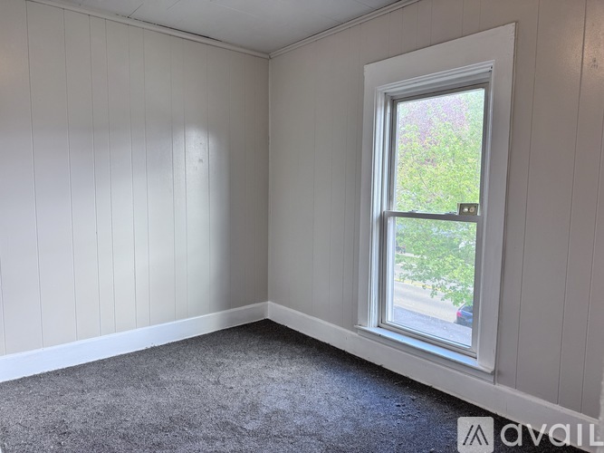 A room with a window and a carpeted floor.