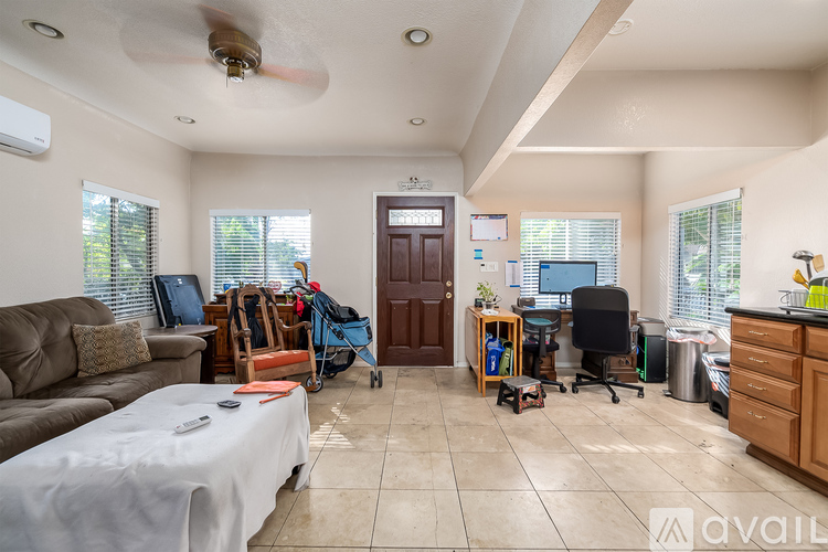 A living room with a couch, a chair, and a table with a white tablecloth on it.