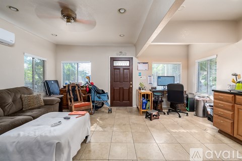 A living room with a couch, a chair, and a table with a white tablecloth on it.