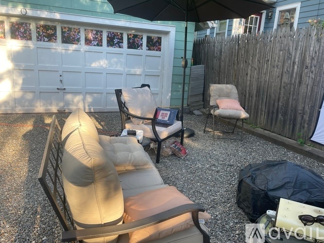 A patio with a black umbrella, a white garage door, and a wooden fence.