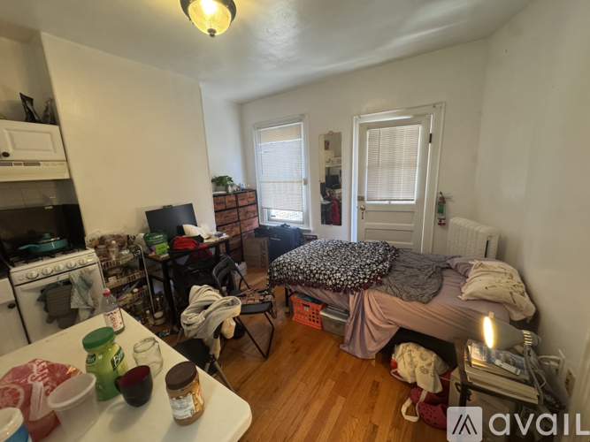 A messy room with a bed, table, and chairs.