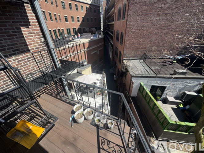 A balcony with a table and chairs overlooks a courtyard.