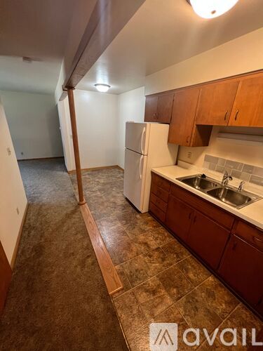 A kitchen with brown tiled floors and wooden cabinets.