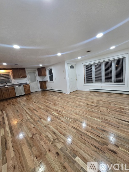 A room with wooden flooring and a window with blinds.