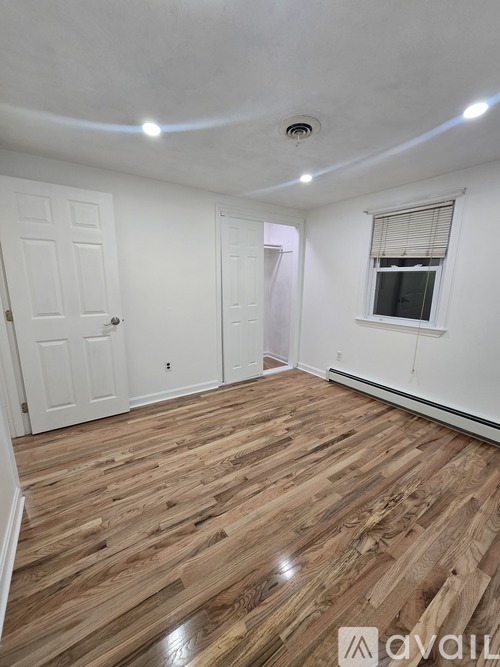 A room with wooden flooring and white walls.