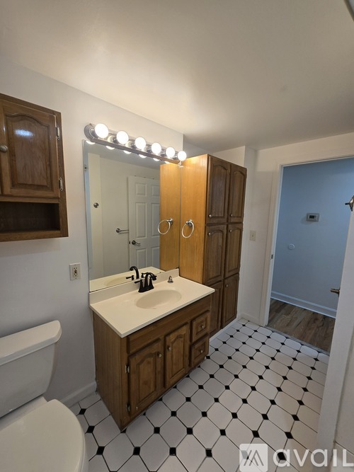 A bathroom with a sink, mirror, and a white tiled floor.