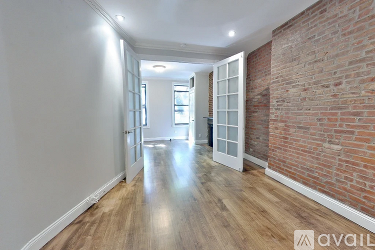 A long hallway with a brick wall on the side and wooden floors.