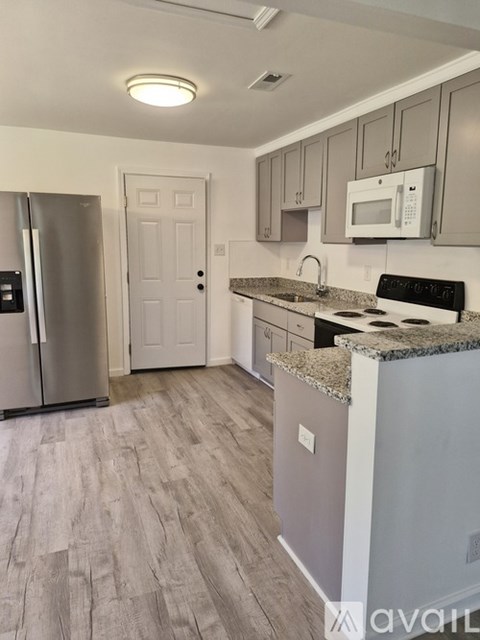 A kitchen with a granite counter top and a stainless steel refrigerator.