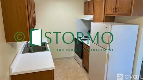 A kitchen with a white fridge and wooden cabinets.