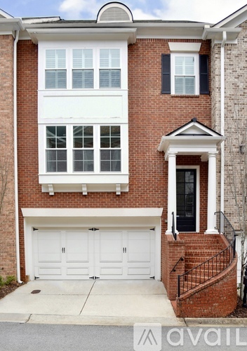A two-story brick house with a white garage door and black shutters.