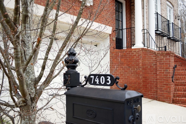 A black mailbox with the number 7403 on it in front of a brick building.
