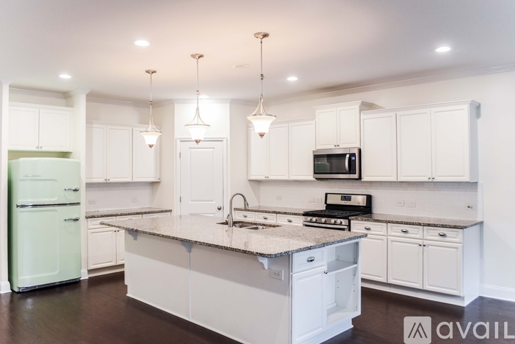 A kitchen with white cabinets and a green fridge.