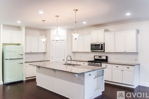 A kitchen with white cabinets and a green fridge.