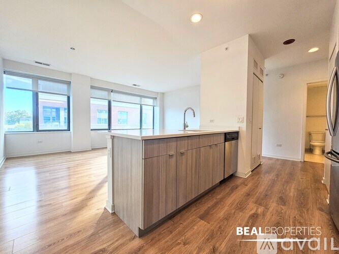 A kitchen area with a counter and cabinets in a room with wooden flooring.