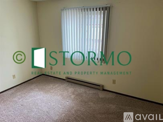 A room with a window covered by blinds and a logo that says "STORM".