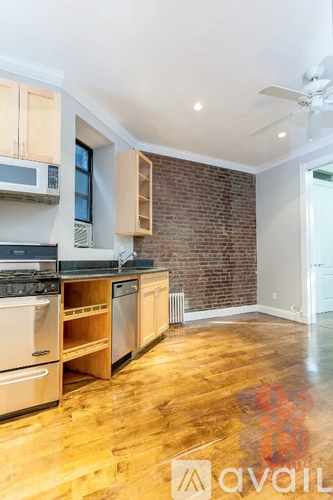 A kitchen with wooden floors and a brick wall.