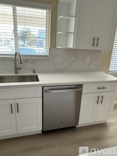 A kitchen with white cabinets and a stainless steel dishwasher.