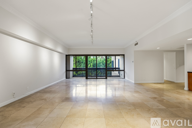 A spacious room with a large window and a view of trees outside.