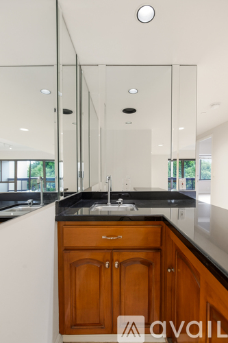 A modern kitchen with wooden cabinets and a large mirror above the sink.