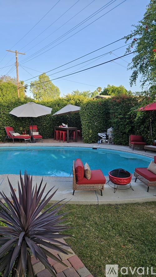 A poolside area with red chairs and umbrellas.