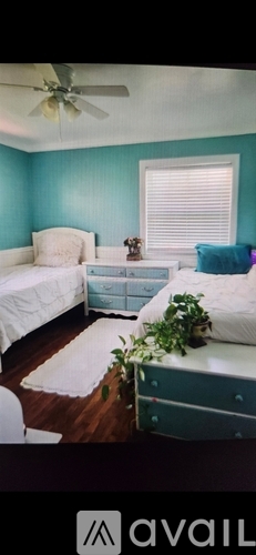 A bedroom with a bed, dresser, and ceiling fan.