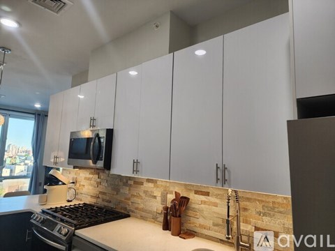 A kitchen with white cabinets and a stone backsplash.