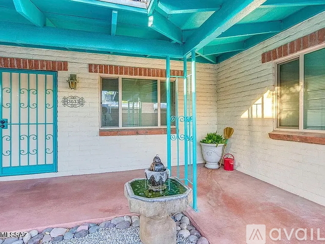 A patio with a fountain and a blue gate.