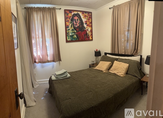 A bedroom with a bed, nightstand, and a painting on the wall.