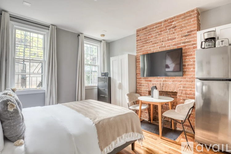 A bedroom with a brick fireplace and a bed with a white comforter.