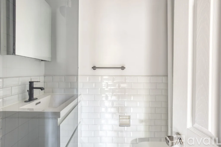 A white tiled bathroom with a sink and toilet paper holder.