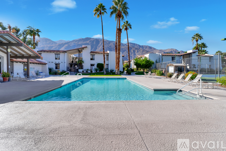 A pool surrounded by palm trees and a mountain in the background.