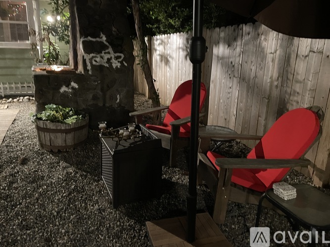 A patio with a red chair and a black umbrella.