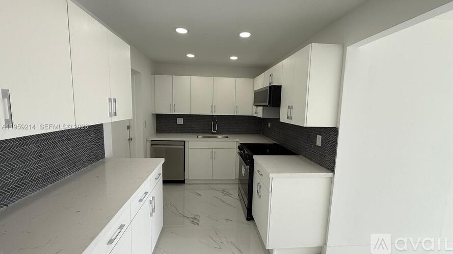 A modern kitchen with white cabinets and a black backsplash.