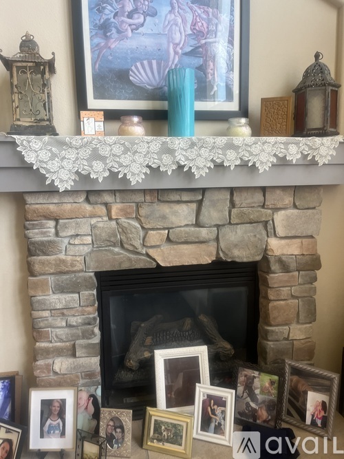 A fireplace mantle with a painting, candle, and lantern.