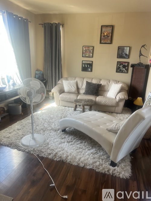 A living room with a white couch and a fan.