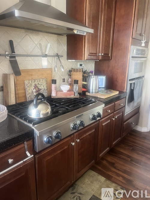 A kitchen with a stove top oven and wooden cabinets.